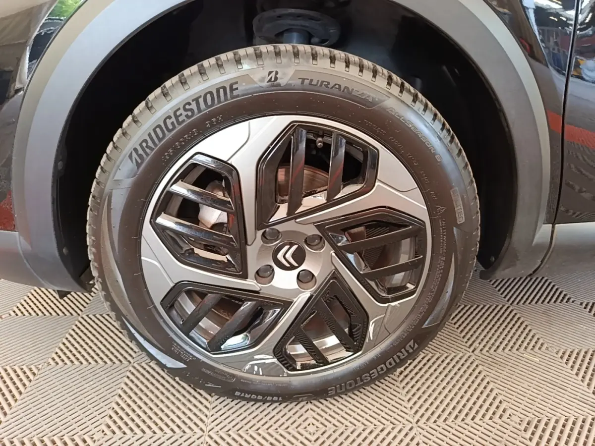 Gros plan sur la roue avant gauche noire d'une Citroën C4 X 2023 avec jante au design moderne bicolore.