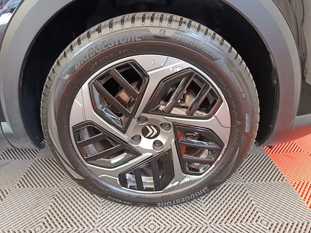 Gros plan sur la roue avant droite noire de la Citroën C4 X avec jante alliage au design moderne.
