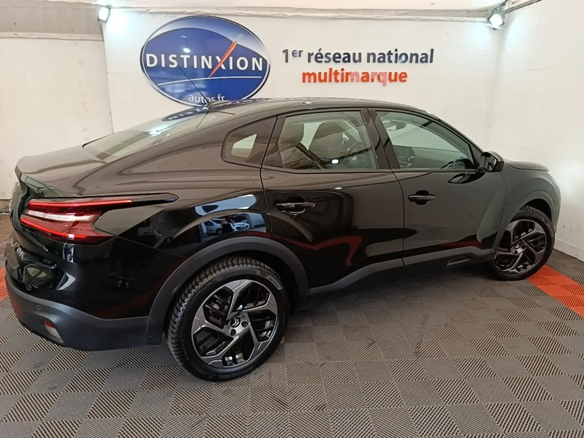 Vue côté droit arrière d'une Citroën C4 X noire 2023 avec feux arrière LED et jantes noires distinctives.