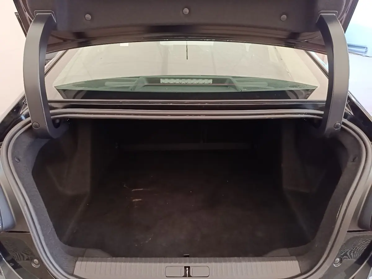 Coffre ouvert vu de l'arrière d'une Citroën C4 X noire, montrant un espace de chargement vide et spacieux.