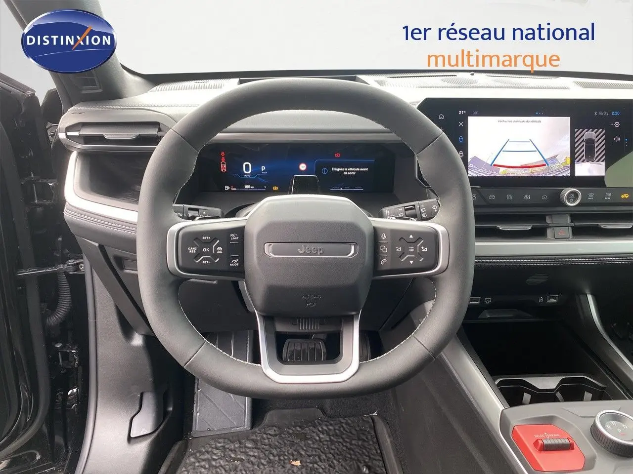 Vue frontale du poste de conduite du Jeep Compass noir Vulcano, avec volant multifonction et écran tactile affichant la caméra de recul.