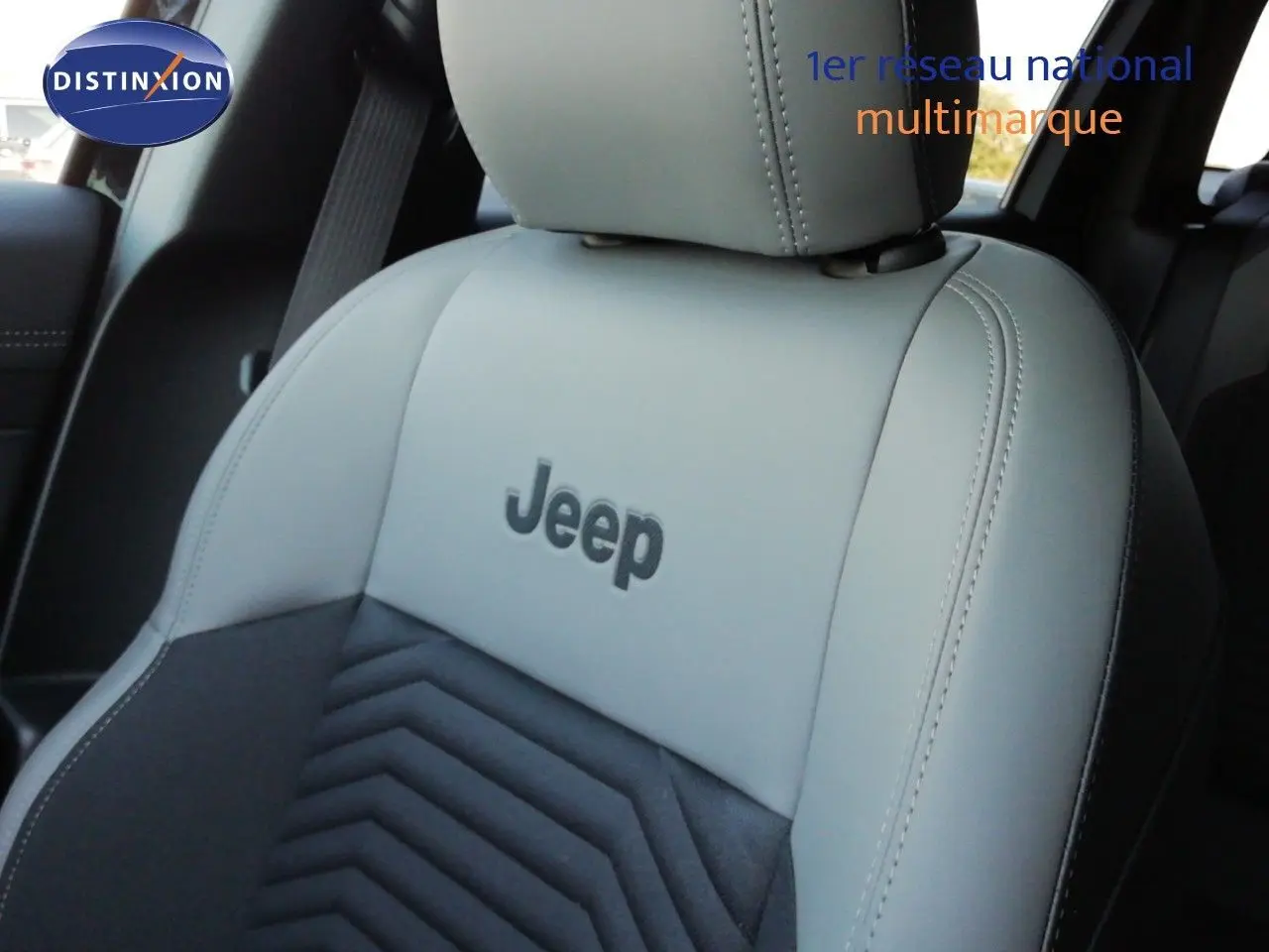 Gros plan sur le siège avant en cuir gris clair et tissu noir du Jeep Compass 2026, logo Jeep brodé au centre.