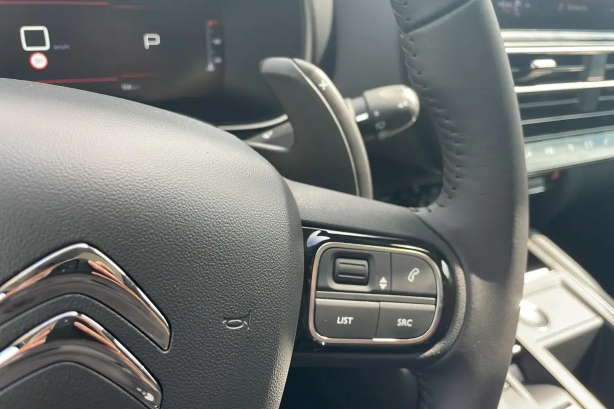 Détail du volant noir du Citroën C5 Aircross Hybrid 2025 avec commandes intégrées et palettes au volant.