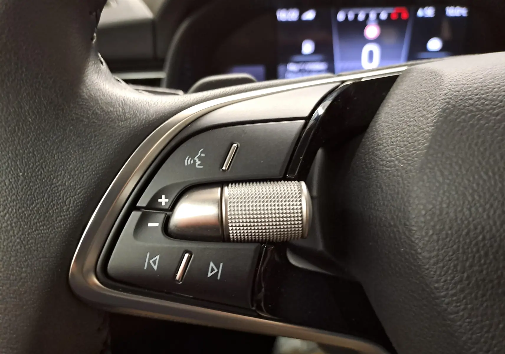 Gros plan sur les commandes gauche du volant du Skoda Kamiq 2025, avec molette métallique et boutons noirs.