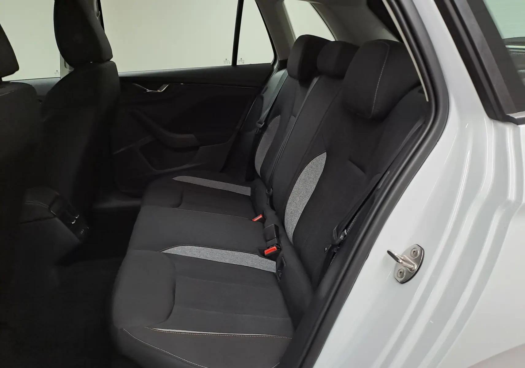 Vue intérieure côté droit des sièges arrière noirs et gris du Skoda Kamiq Blanc Lune avec porte ouverte.