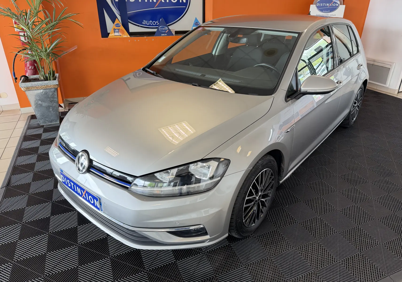 Volkswagen Golf TSI 130 Confortline gris vue 3/4 avant droit en intérieur avec jantes noires multibranches.