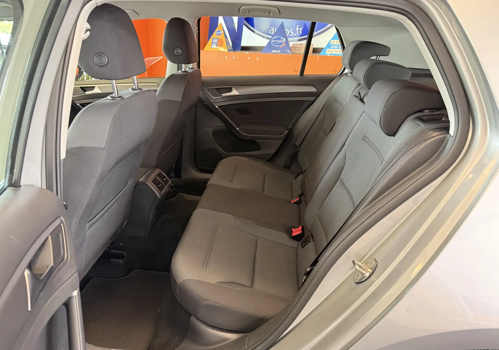Vue intérieure arrière côté gauche d'une Volkswagen Golf TSI 130 Confortline gris, montrant les sièges arrière en tissu gris.