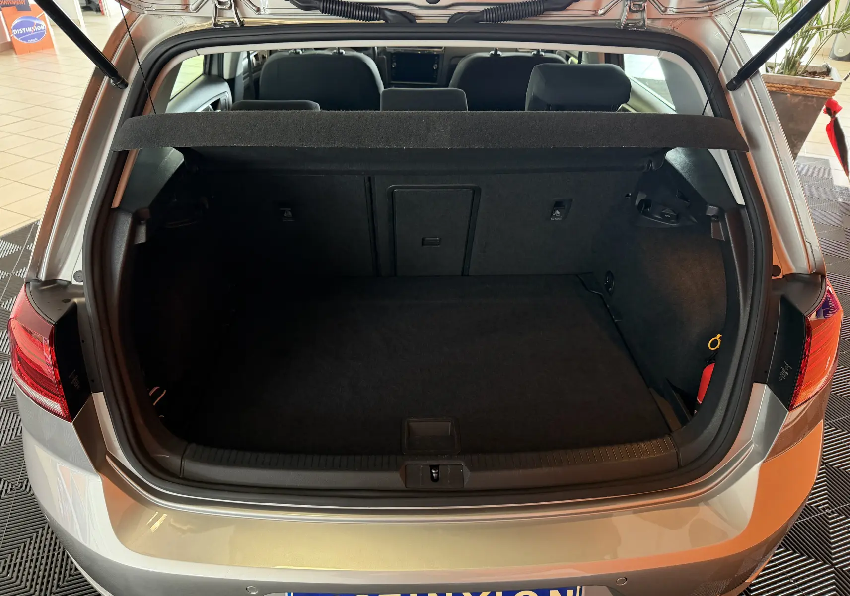 Coffre ouvert vu de l’arrière d’une Volkswagen Golf TSI 130 Confortline gris, intérieur spacieux et banquette arrière visible.