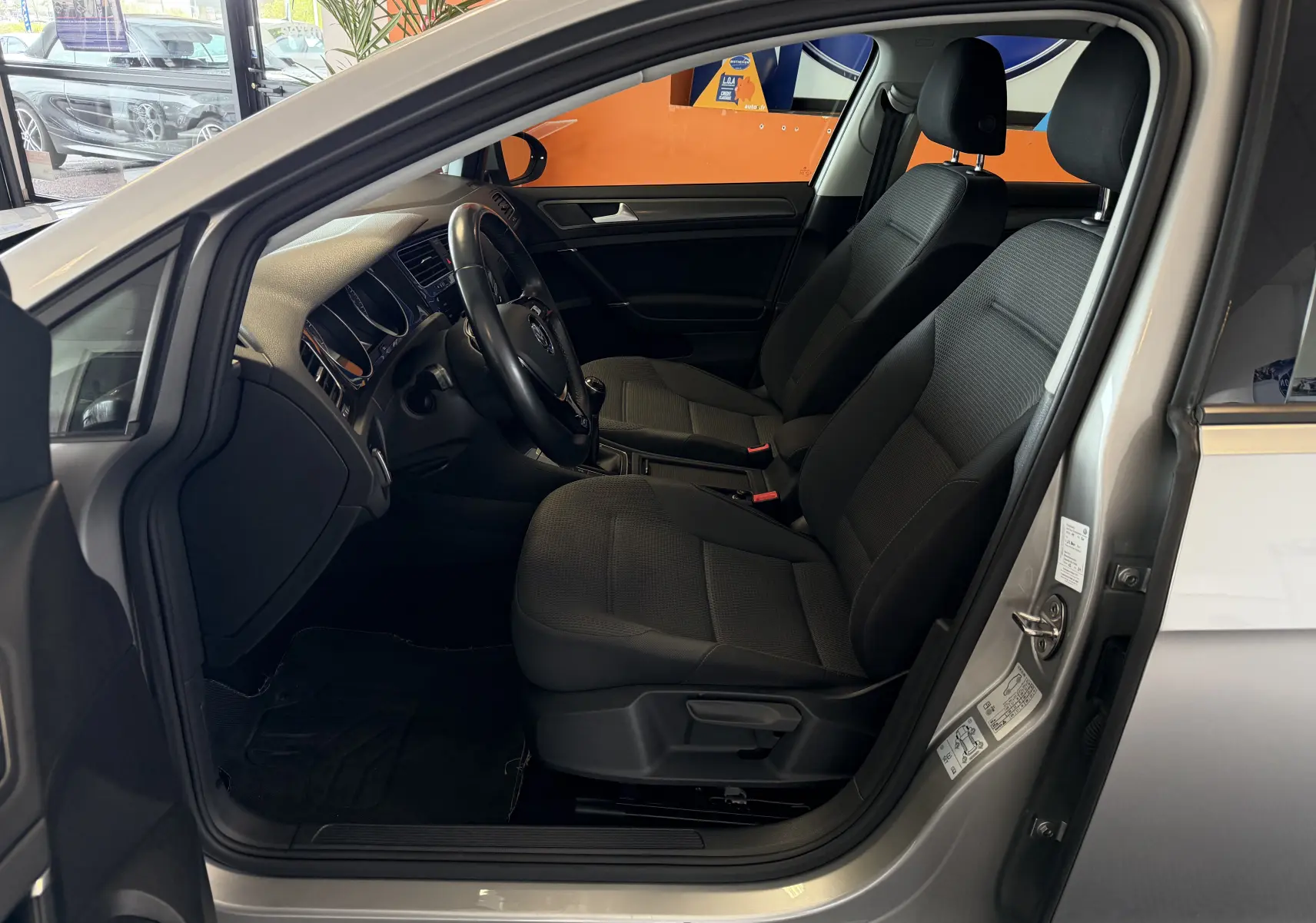 Vue intérieure côté conducteur d'une Volkswagen Golf TSI 130 Confortline gris, montrant sièges et tableau de bord.