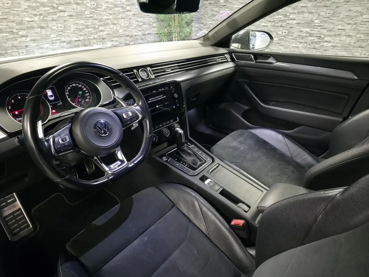 Vue intérieure côté conducteur du Volkswagen Arteon 2.0 TSI gris, avec volant cuir R-Line et console centrale moderne.