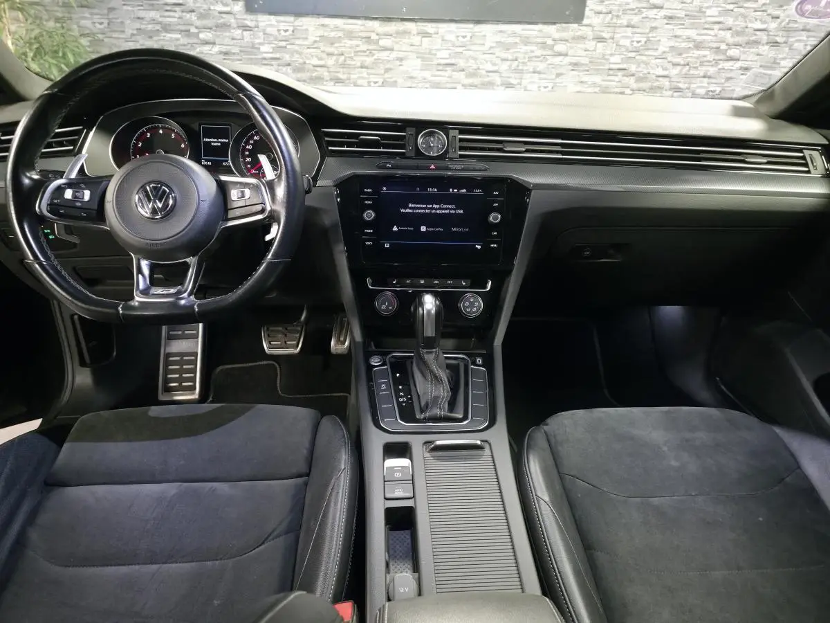 Vue intérieure frontale du Volkswagen Arteon 2020, tableau de bord noir avec volant cuir multifonction R-Line et console centrale.