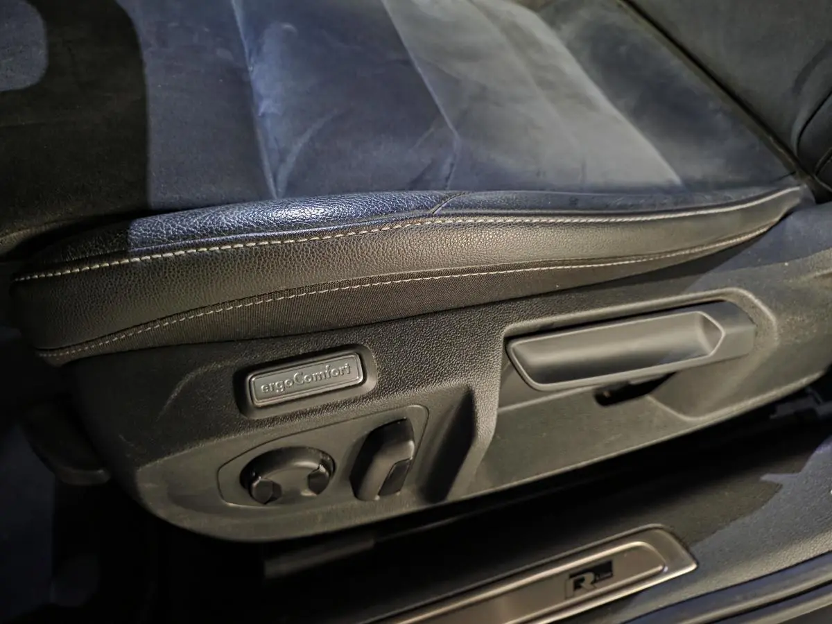 Gros plan sur le réglage électrique du siège avant gauche en cuir noir avec badge ergoComfort et seuil de porte R-Line.