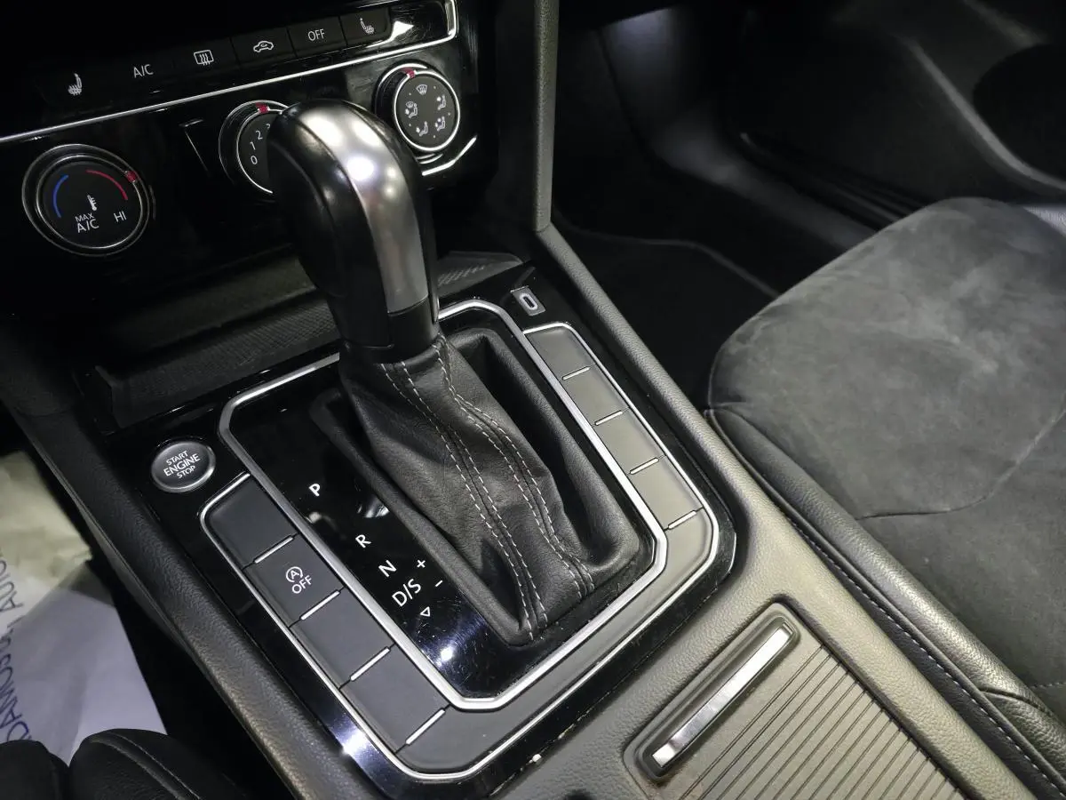 Gros plan sur la console centrale noire avec levier de vitesse automatique cuir et boutons de commande d’une Volkswagen Arteon gris.
