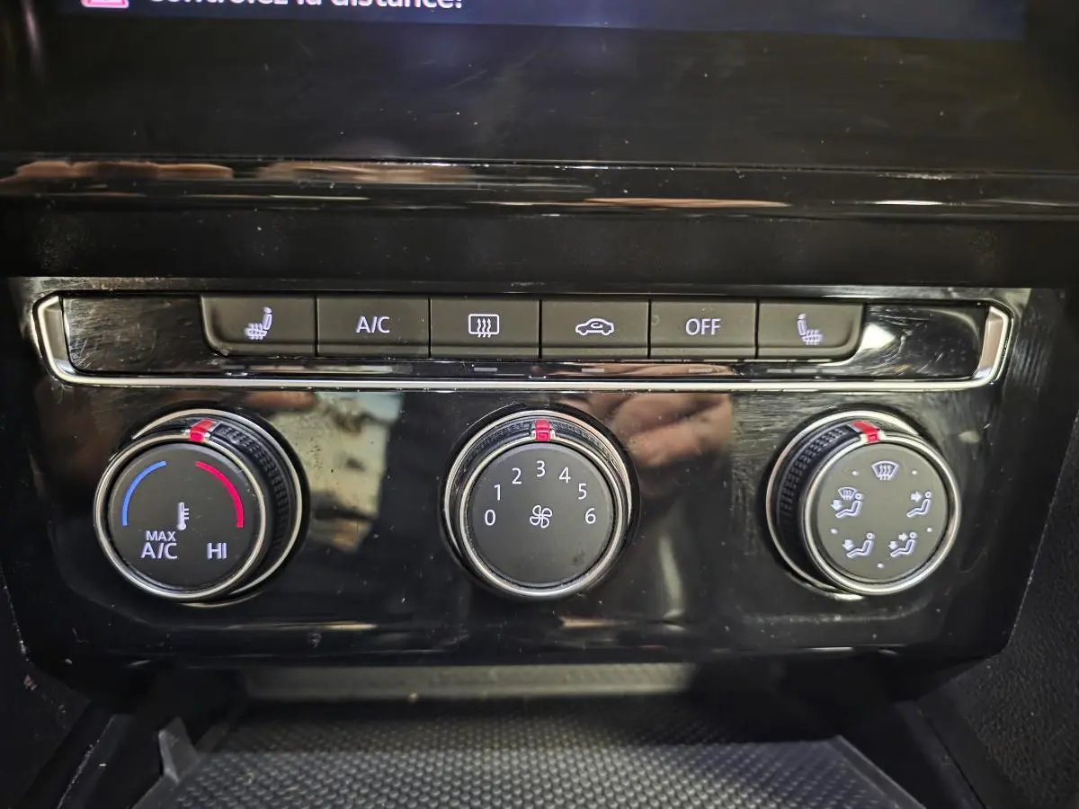 Gros plan sur la console centrale noire brillante du Volkswagen Arteon 2020 avec commandes de climatisation manuelles.