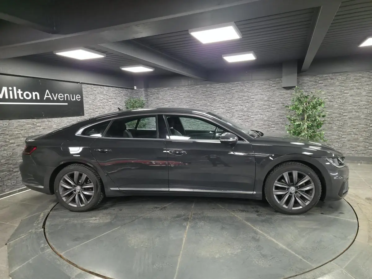 Vue latérale droite d'une Volkswagen Arteon gris foncé R-Line 2020 en intérieur avec jantes alliage 18 pouces.