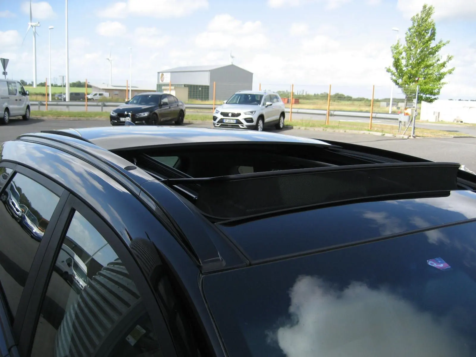 Vue en plongée du toit ouvrant ouvert sur le côté gauche d’un Hyundai Tucson noir fantom metal stationné en extérieur.