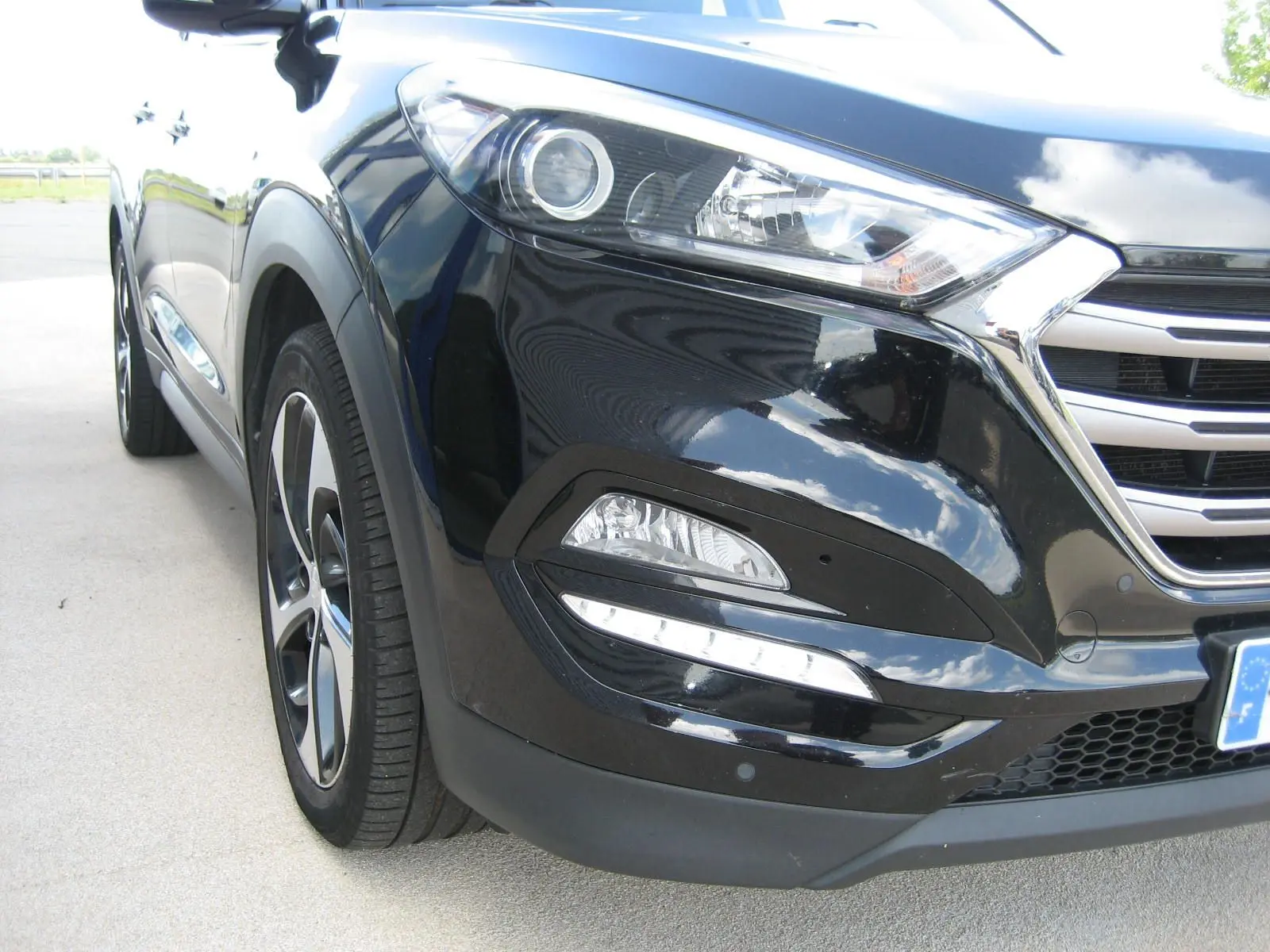 Vue 3/4 avant gauche du Hyundai Tucson noir fantom metal, mettant en valeur les phares LED et la calandre chromée.