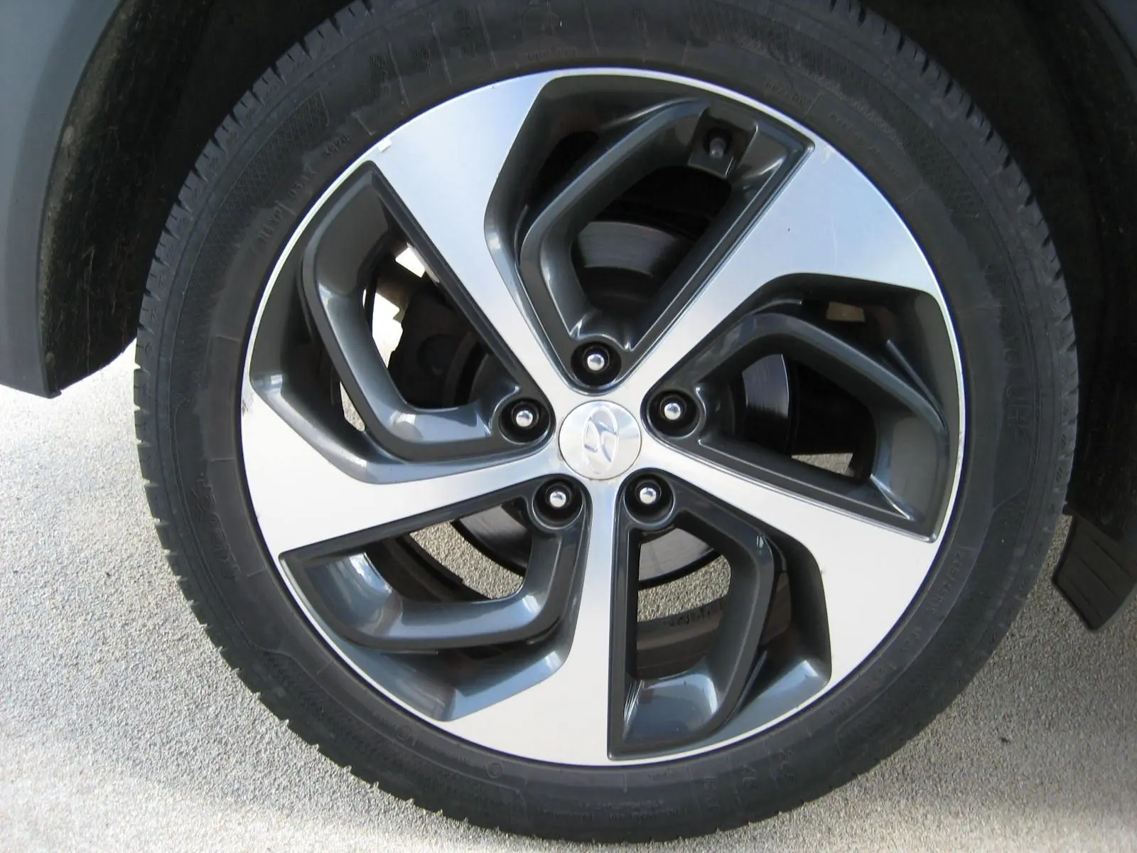 Vue rapprochée sur la roue arrière gauche d'un Hyundai Tucson noir fantom metal, soulignant le pneu et l'aile du véhicule.