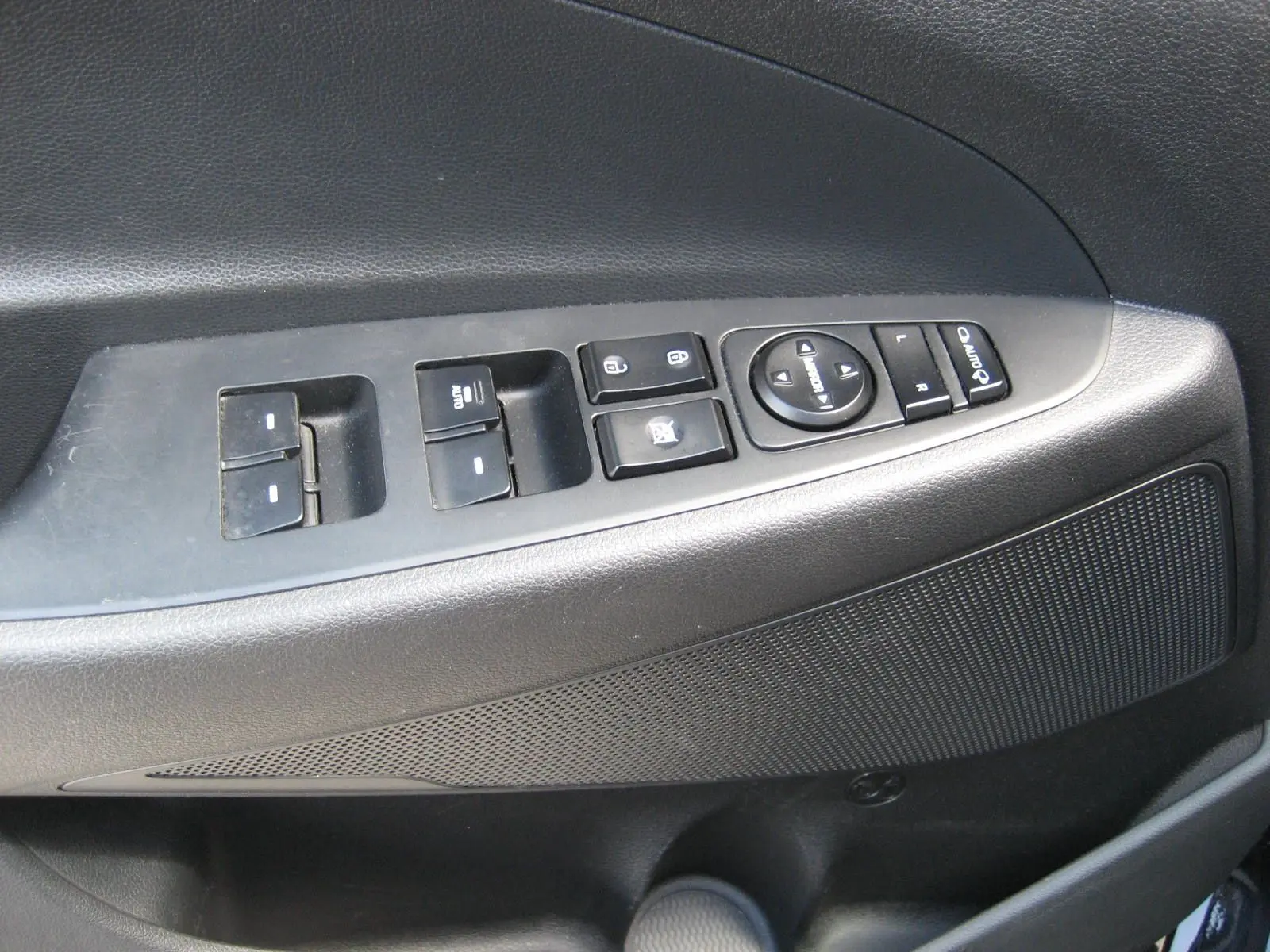 Gros plan sur la commande des vitres et rétroviseurs côté conducteur d’un Hyundai Tucson noir fantom metal de 2016.
