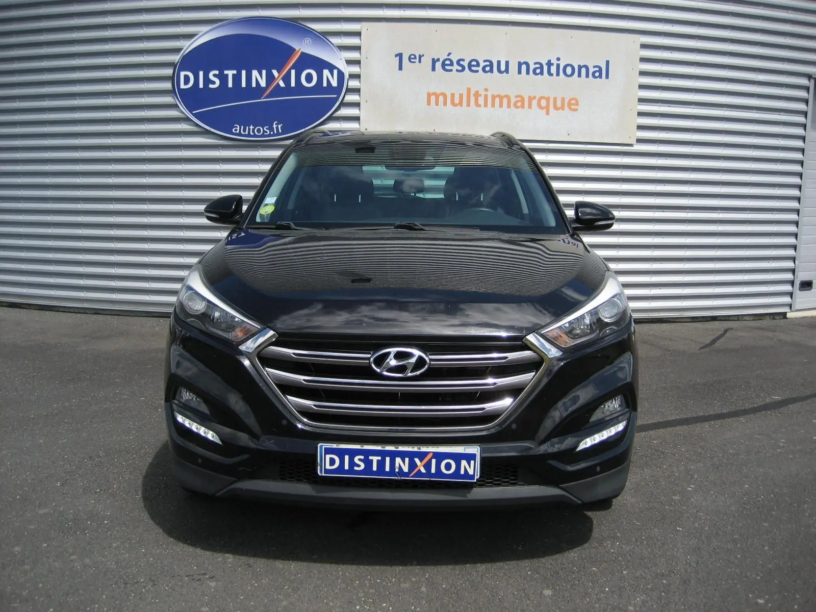 Vue avant d'un Hyundai Tucson noir fantom metal 2016 avec calandre chromée et feux LED allumés.