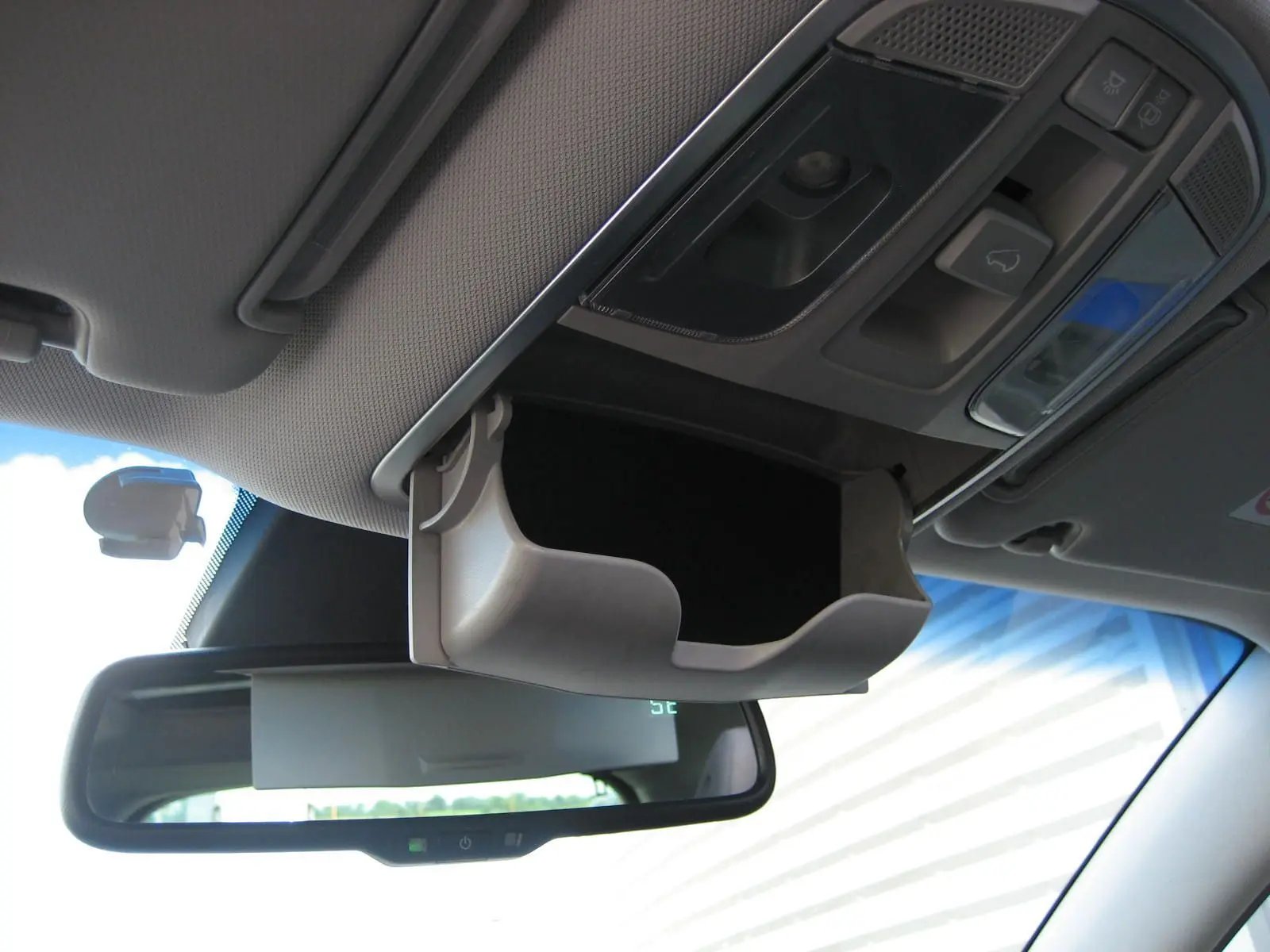 Vue intérieure du rangement lunettes ouvert au plafond d'un Hyundai Tucson noir, avec rétroviseur et commandes de toit visibles.
