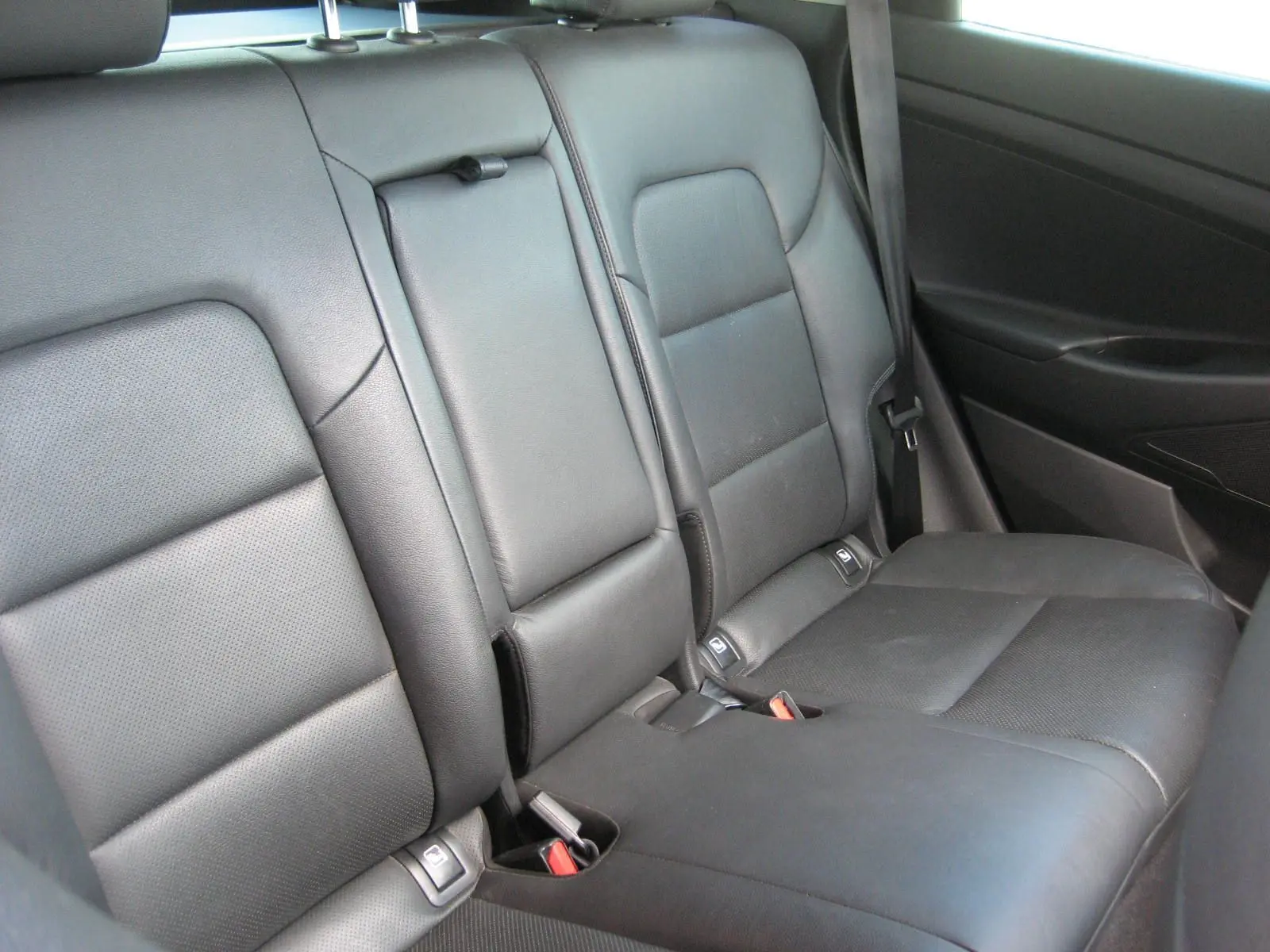 Vue intérieure montrant la banquette arrière en cuir noir avec accoudoir central relevé du Hyundai Tucson 2016.