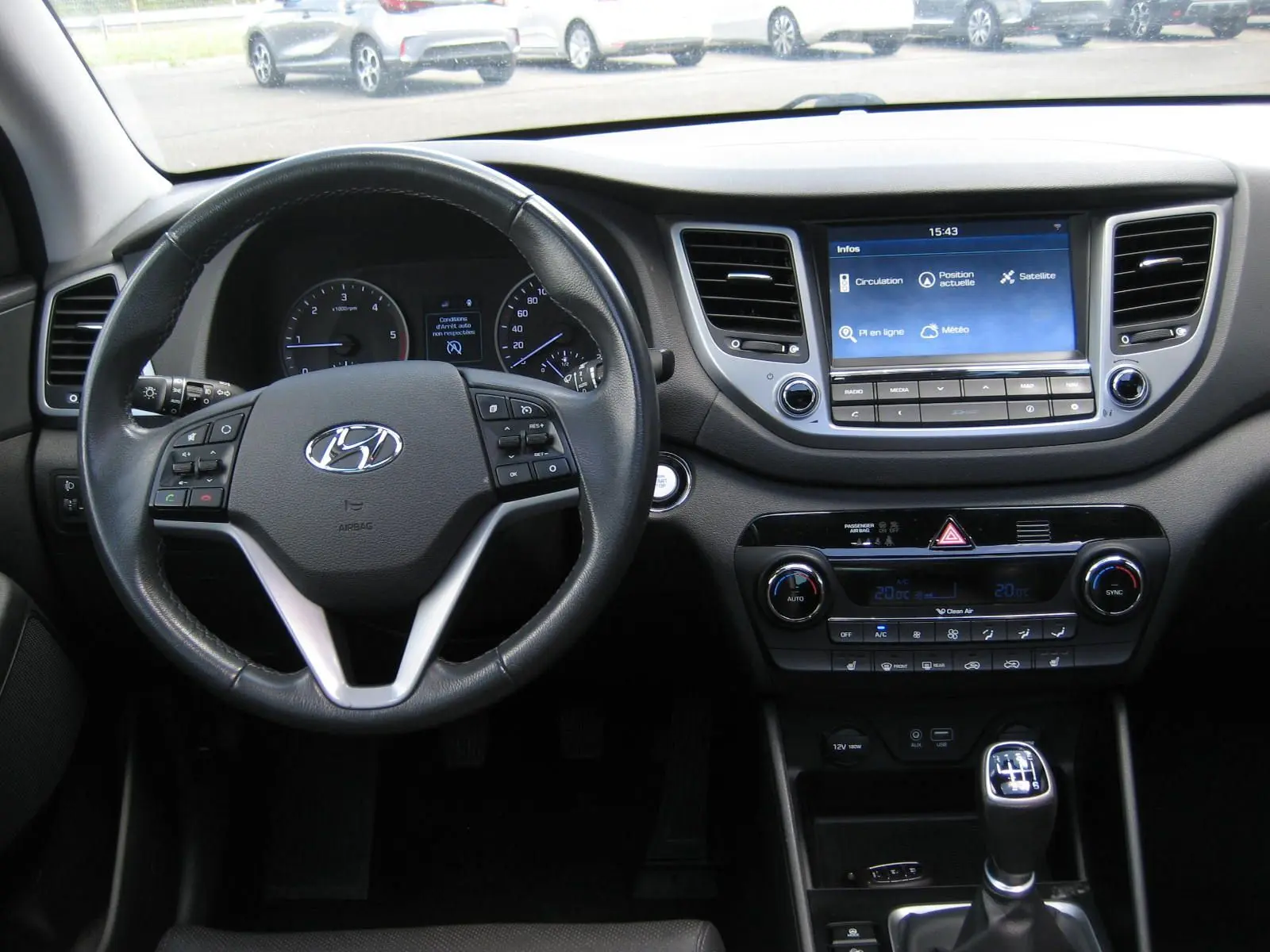 Vue intérieure du tableau de bord du Hyundai Tucson 2016, avec volant cuir noir et écran tactile central allumé.