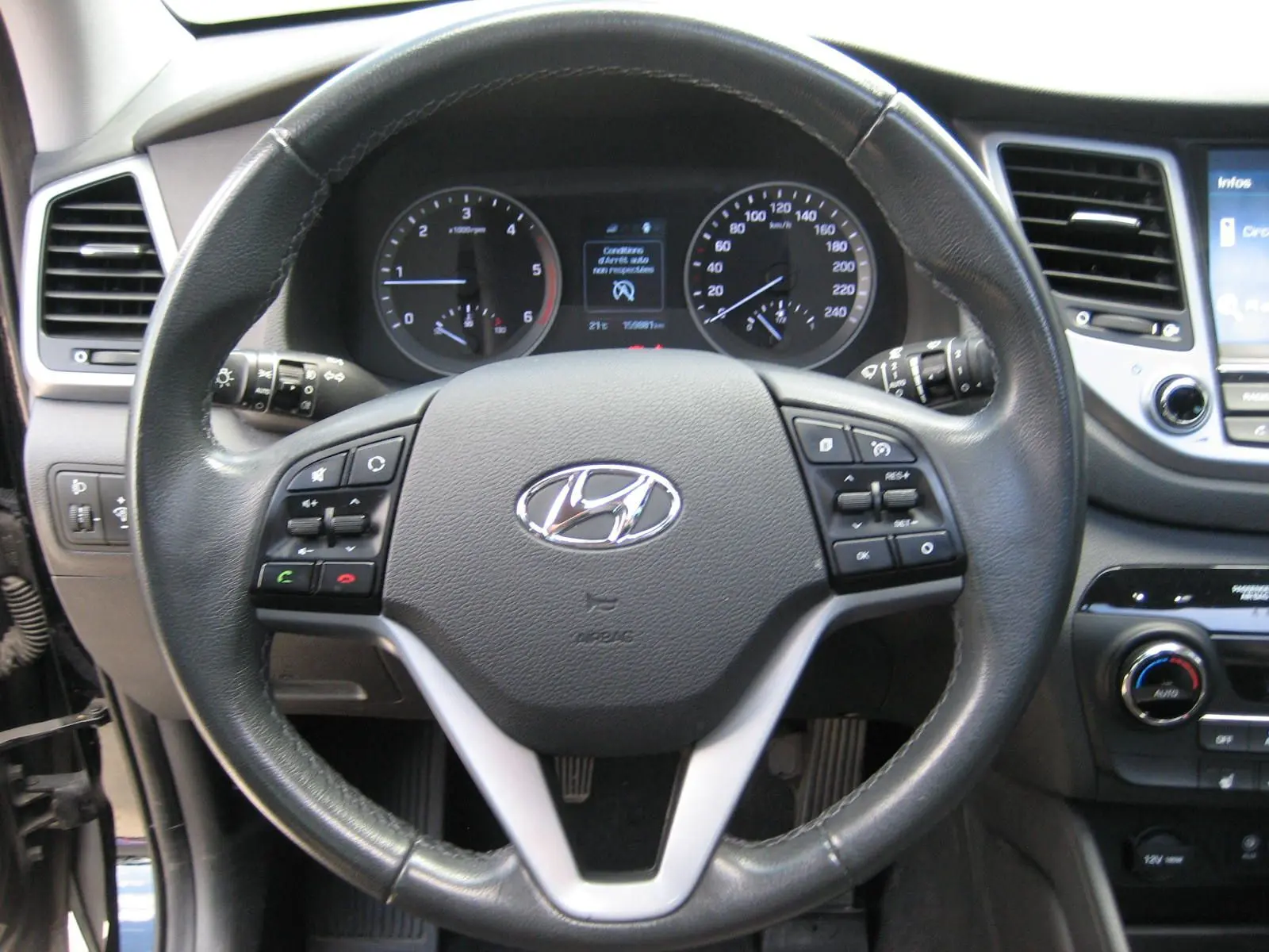 Vue rapprochée du volant en cuir noir du Hyundai Tucson 2016, avec tableau de bord et commandes visibles.