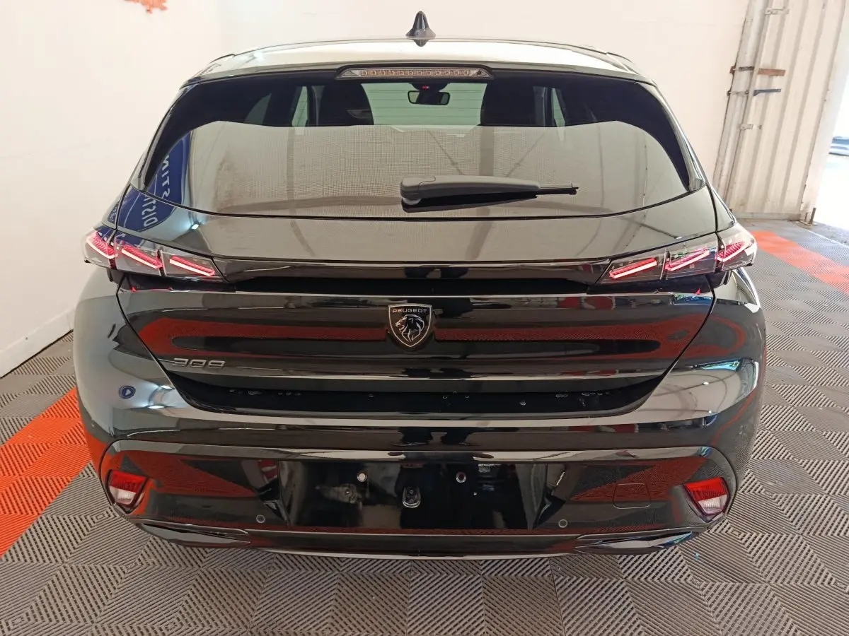 Vue arrière d'une Peugeot 308 noire 2026 avec feux LED distinctifs et logo lion central sur hayon.