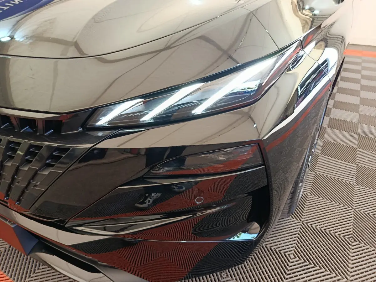 Gros plan sur l'avant droit noir brillant de la Peugeot 308 2026 avec phares LED allumés et calandre distinctive.