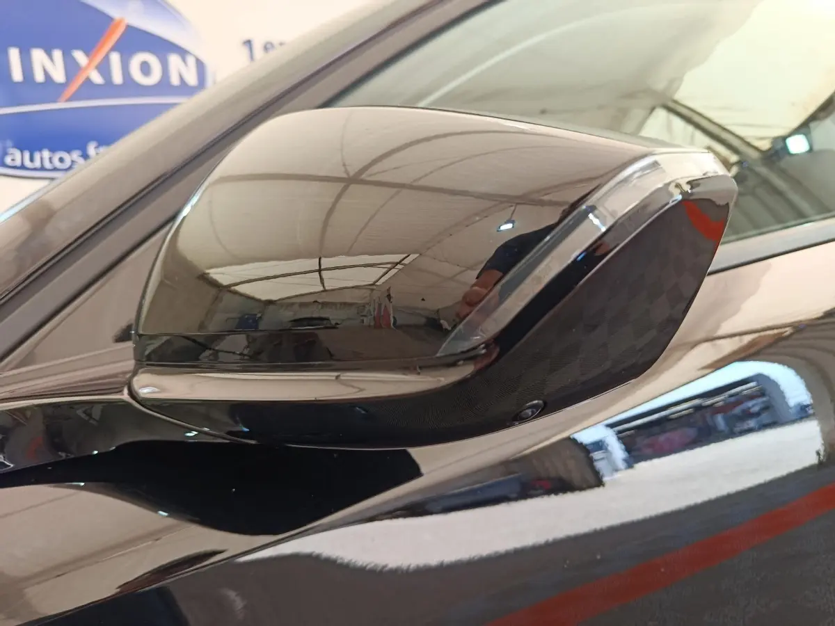 Rétroviseur côté gauche noir brillant de la Peugeot 308 2026, reflet d'un garage intérieur visible.