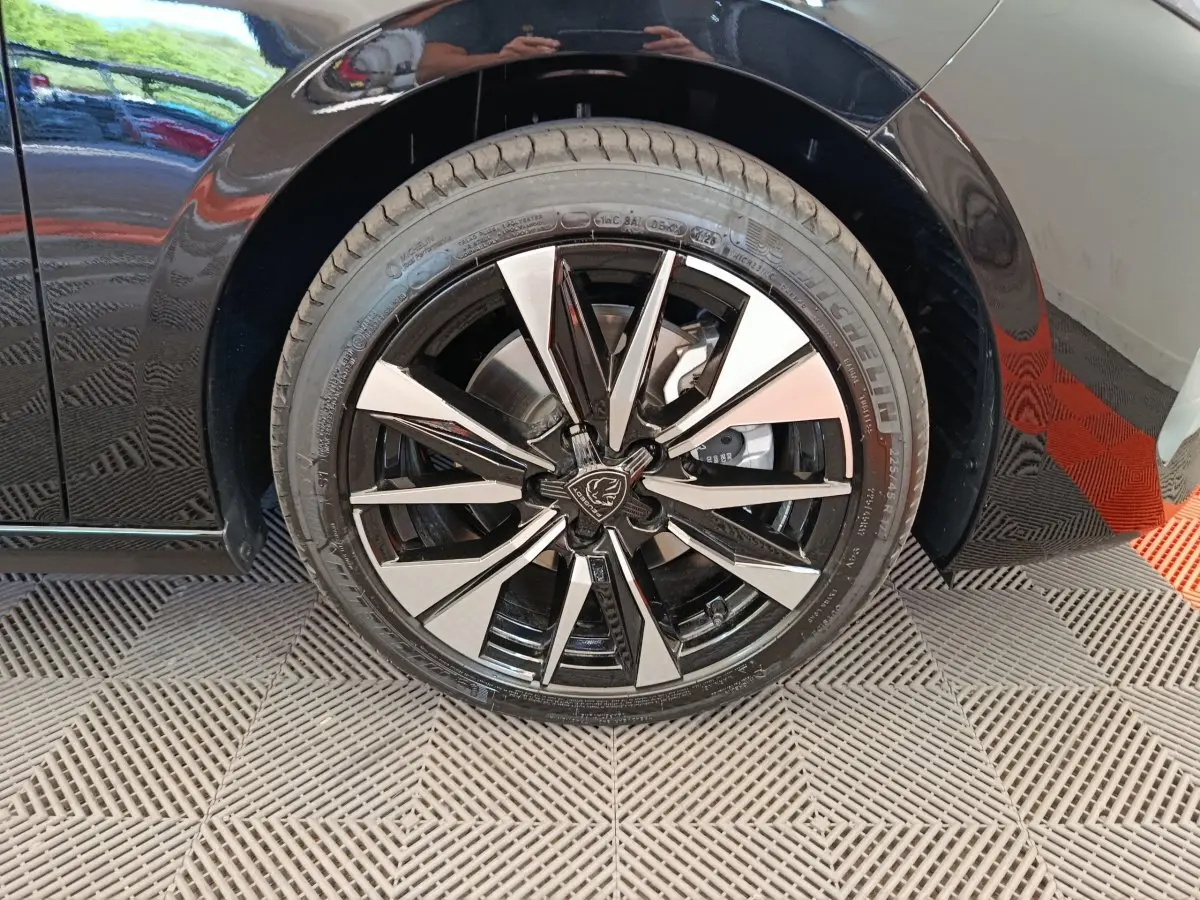 Gros plan sur la roue avant gauche noire d’une Peugeot 308 2026, jante alliage bicolore au design moderne.