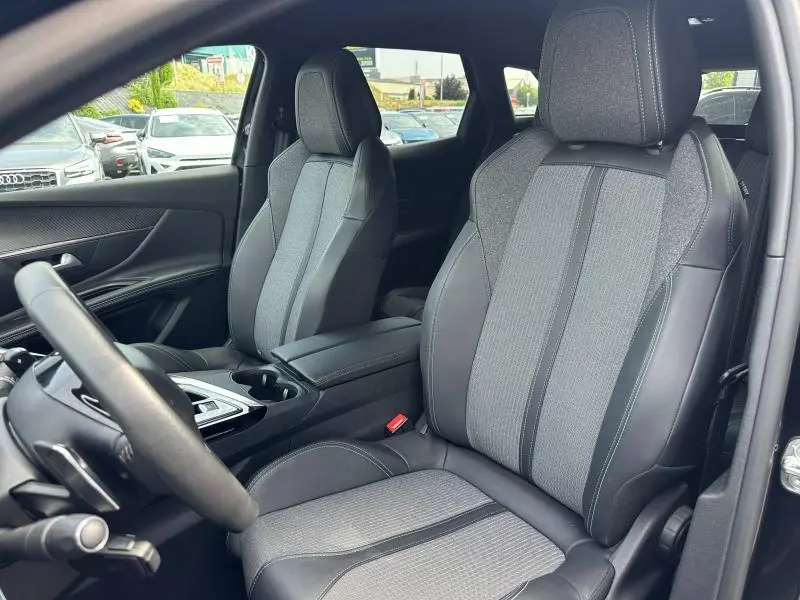 Vue intérieure côté conducteur du Peugeot 3008 Hybride Rechargeable 2024, sièges tissu et cuir noir avec surpiqûres grises.