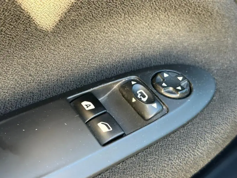 Gros plan sur les commandes de réglage des rétroviseurs et des vitres côté conducteur d'une DS3 noire de 2016.