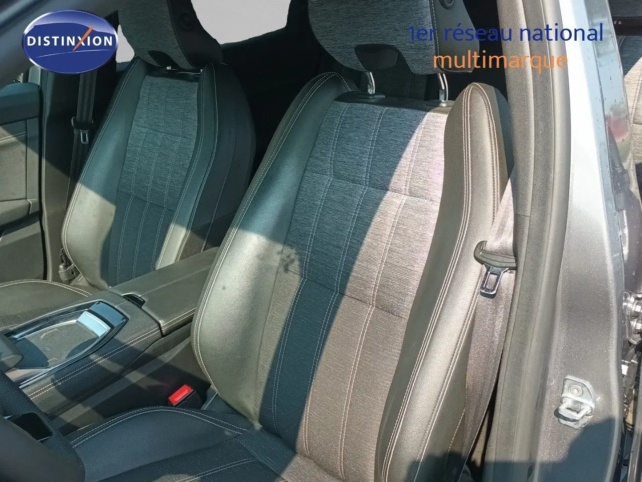 Vue intérieure sur les sièges avant en tissu et cuir gris du Renault Austral E-Tech 2025, avec console centrale visible.