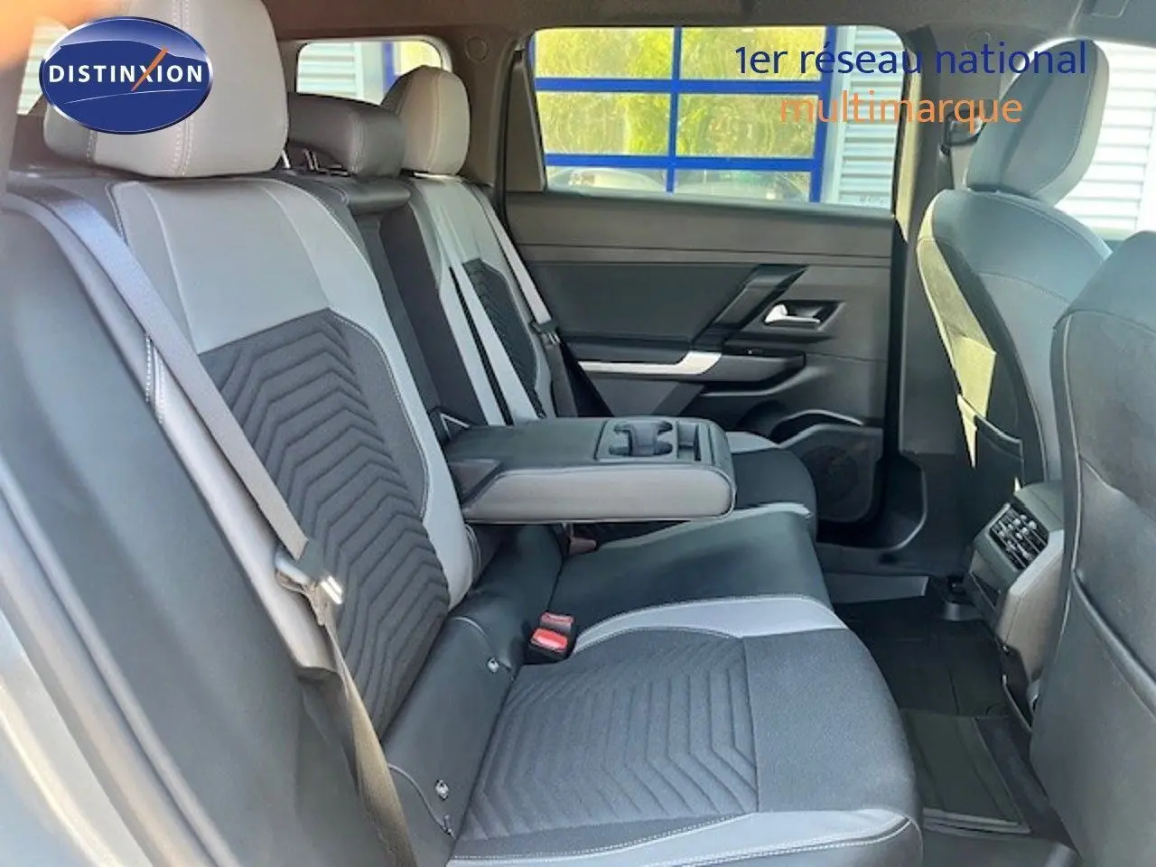 Vue intérieure arrière du Jeep Compass 2026, sièges bicolores gris clair et foncé avec accoudoir central déployé.
