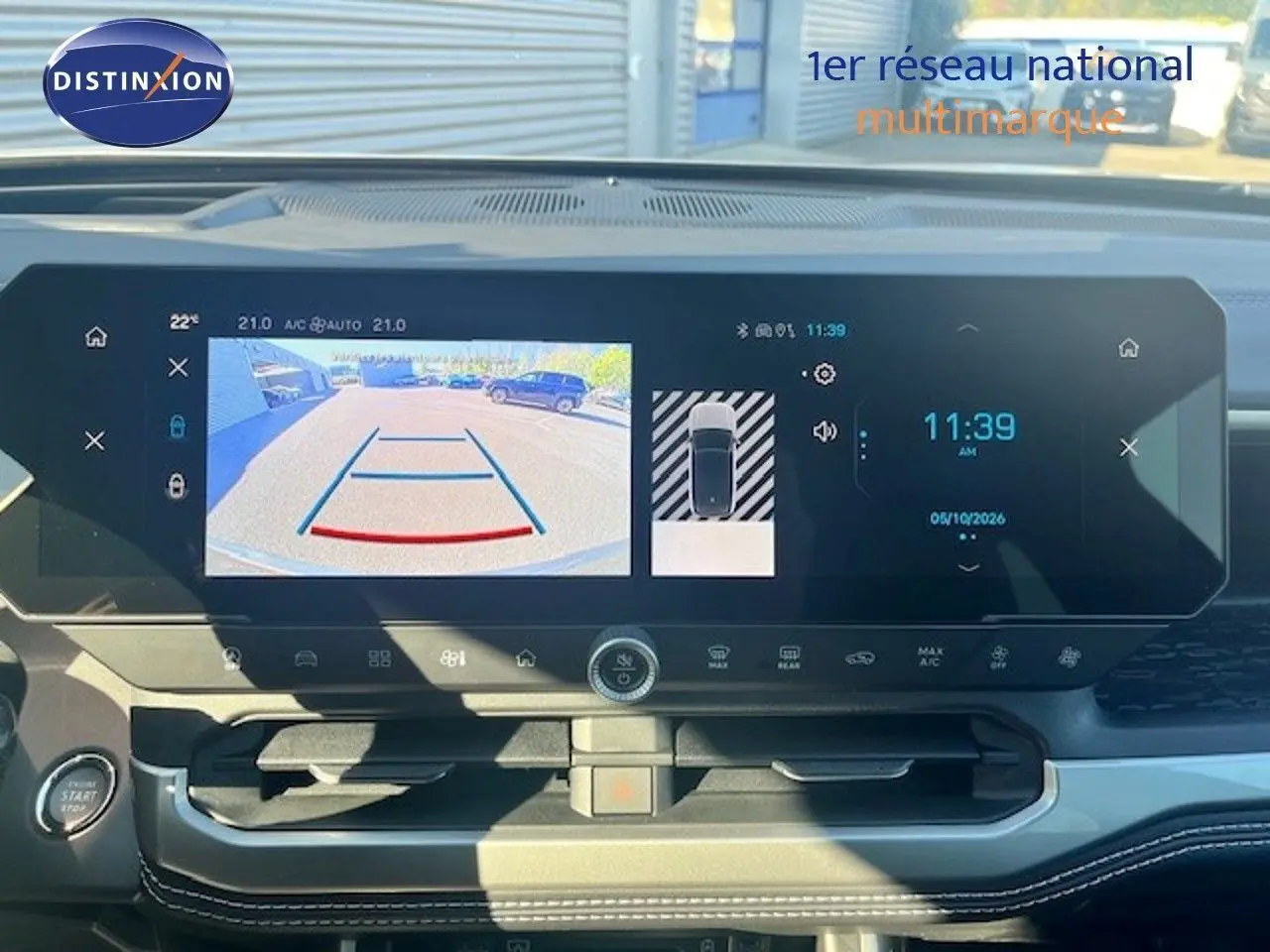 Vue intérieure du tableau de bord du Jeep Compass 2026, écran tactile affichant la caméra de recul et l'horloge digitale.