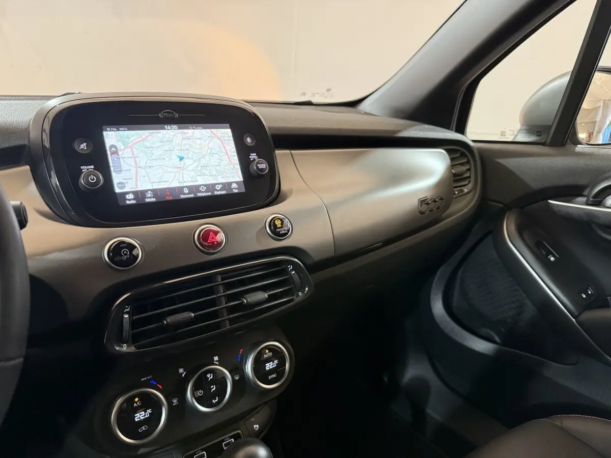 Vue intérieure côté passager du tableau de bord beige et noir avec écran tactile et logo 500 de la Fiat 500X 2021.