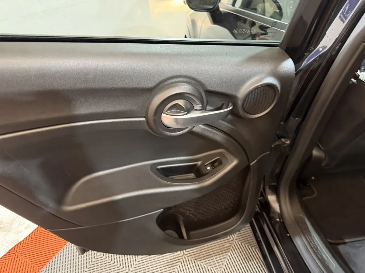 Gros plan sur la porte arrière gauche noire de la FIAT 500X 2021 avec poignée argentée et haut-parleur intégré.