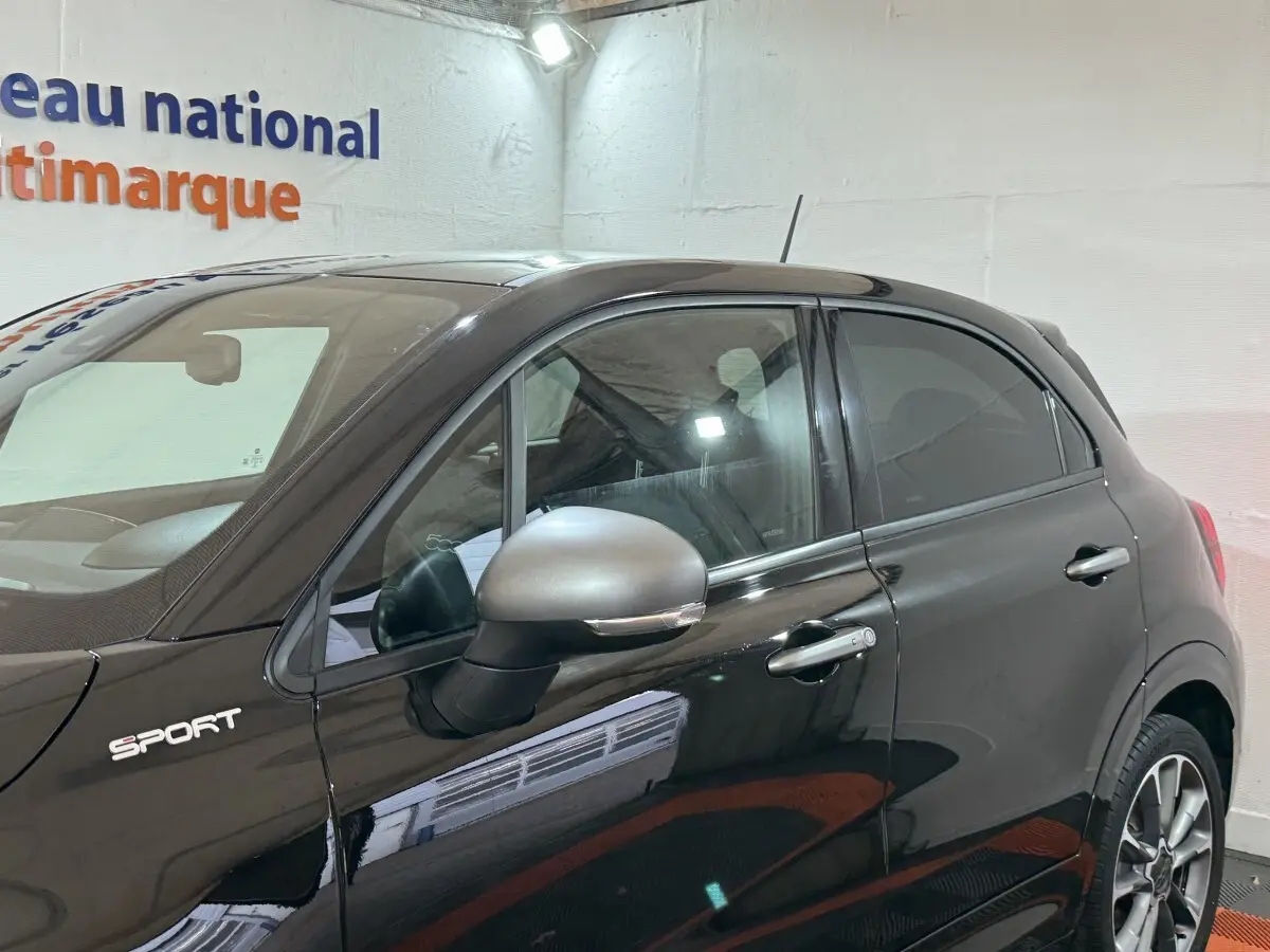 Profil côté gauche d'une FIAT 500X noire version Sport 2021 avec rétroviseur gris et jantes alliage visibles.
