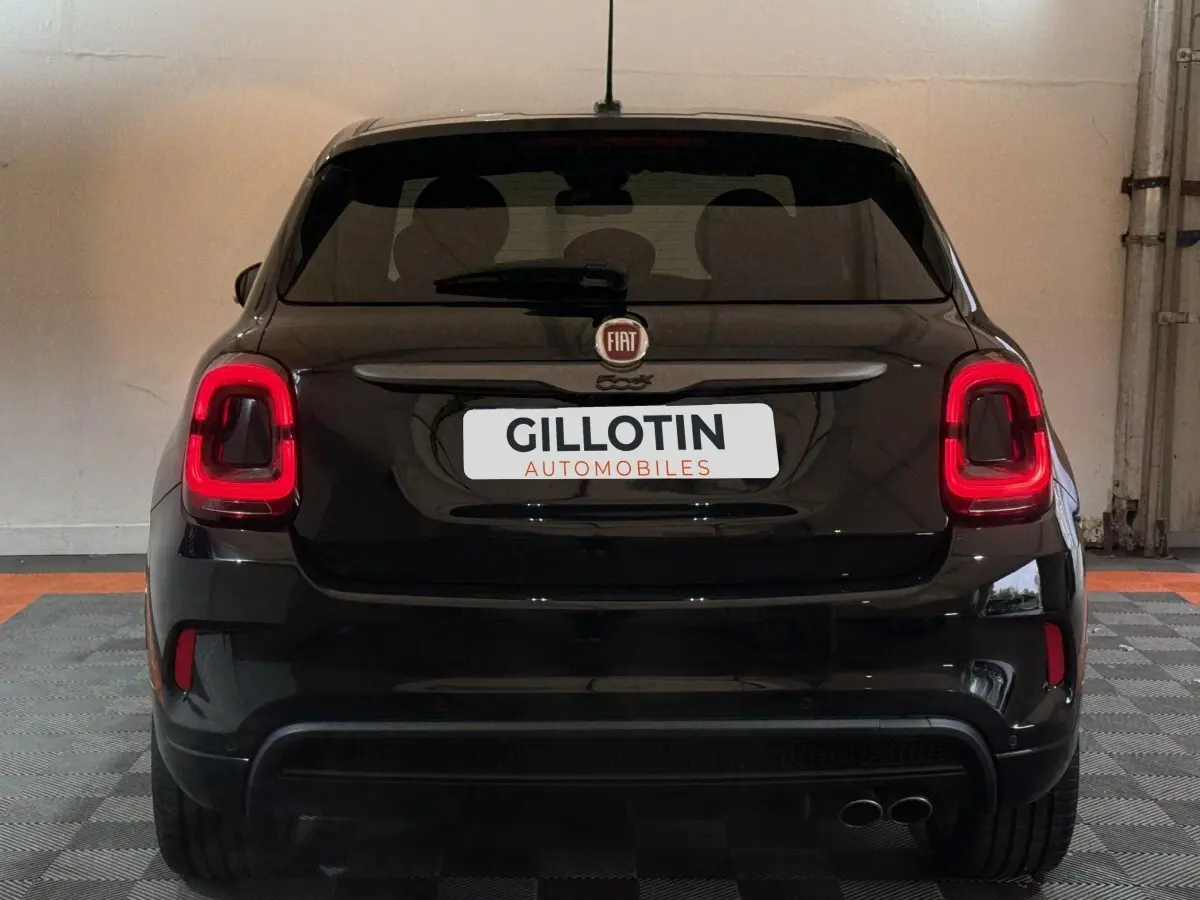 Vue arrière d'un FIAT 500X noir avec feux arrière LED et double sortie d'échappement visible en intérieur.