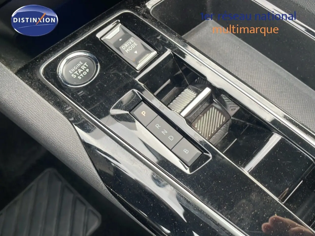 Gros plan sur la console centrale noire brillante du Peugeot 3008 hybride 2024 avec bouton start/stop et sélecteur de boîte auto.