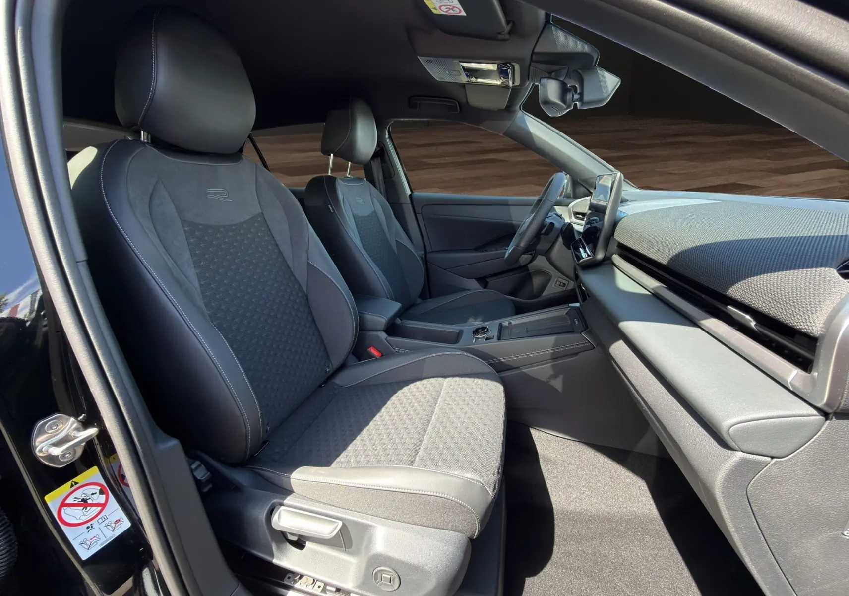 Vue intérieure côté conducteur du Volkswagen T-Roc 2026 noir ébène, sièges en tissu et cuir avec logo R brodé.
