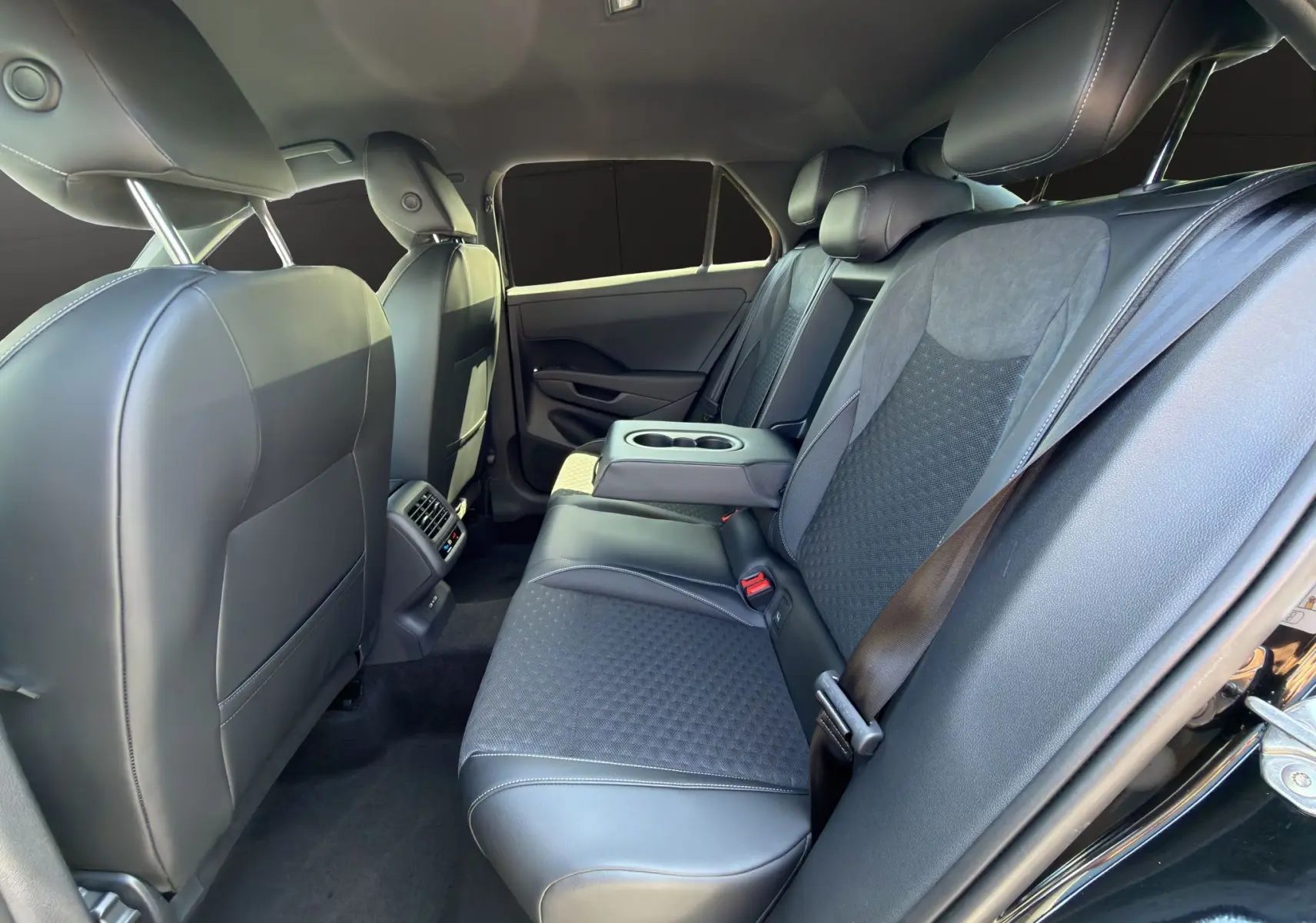 Vue intérieure côté droit des sièges arrière en cuir et tissu noir du Volkswagen T-Roc 2026, avec accoudoir central rabattable.