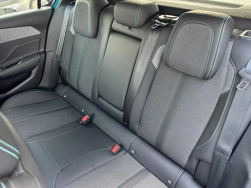 Vue rapprochée de la banquette arrière en tissu et cuir noir avec surpiqûres bleues du Peugeot 308 2024.