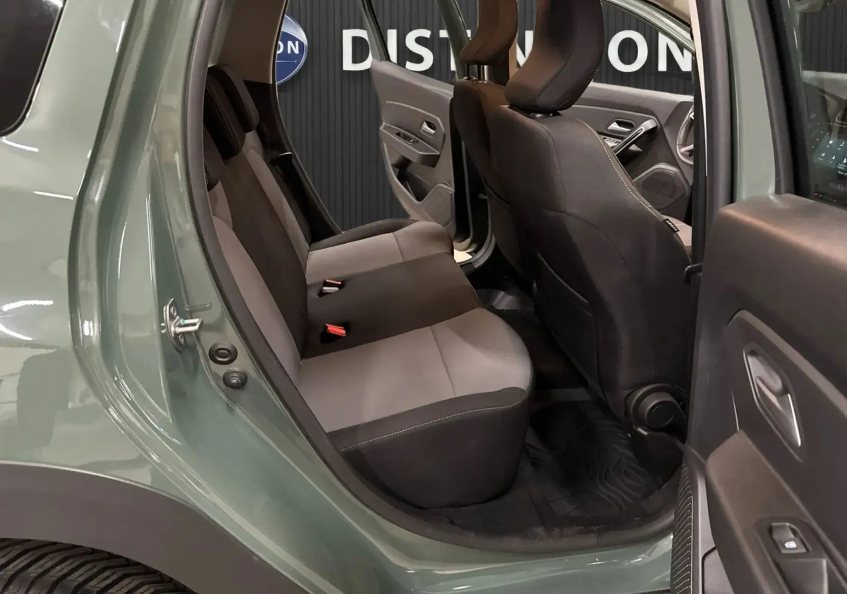 Vue intérieure côté arrière droit du Dacia Duster 2024 kaki lichen, montrant les sièges arrière en tissu gris et noir.