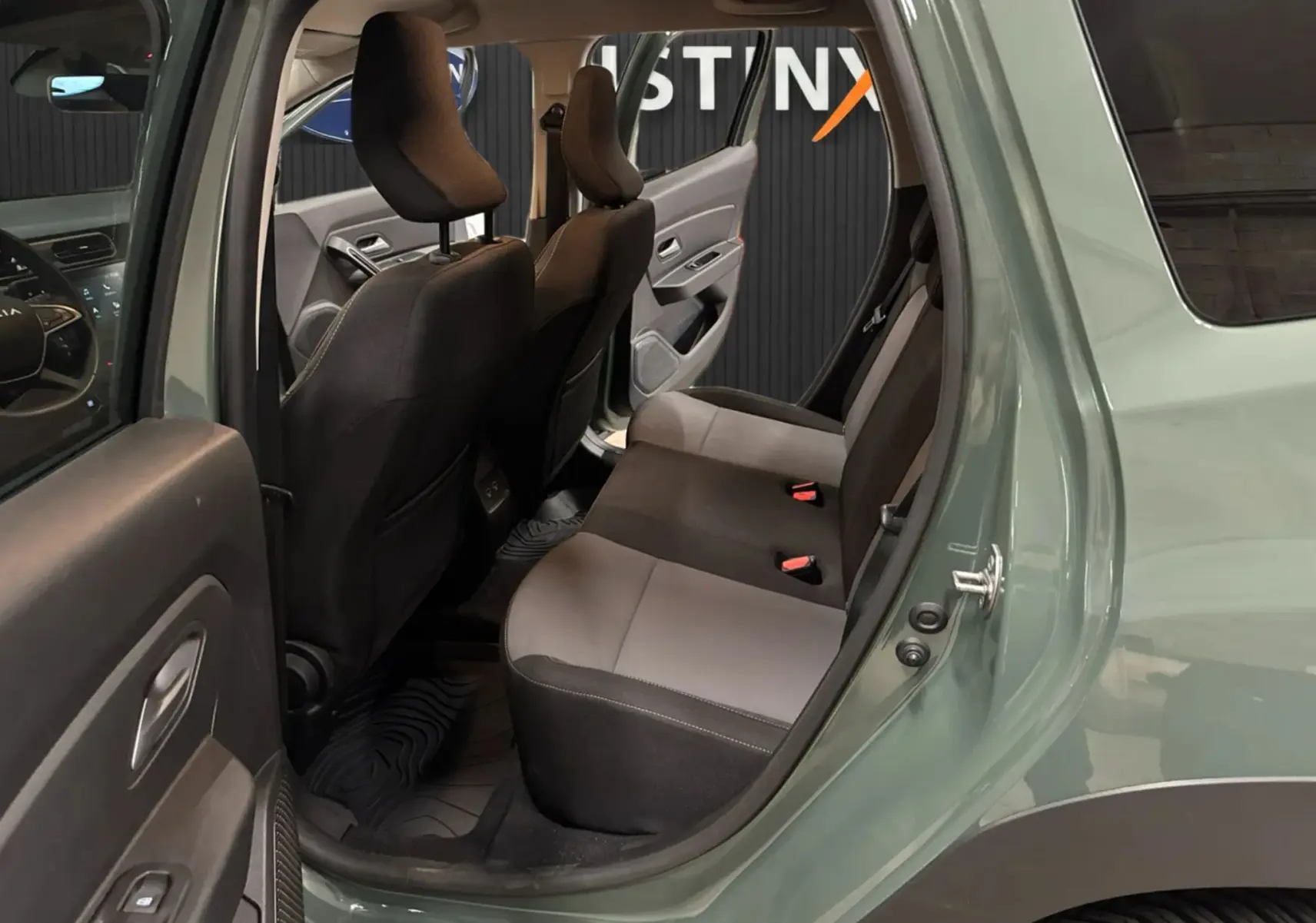 Vue intérieure côté droit arrière du Dacia Duster 2024 kaki lichen, montrant les sièges arrière et la porte ouverte.