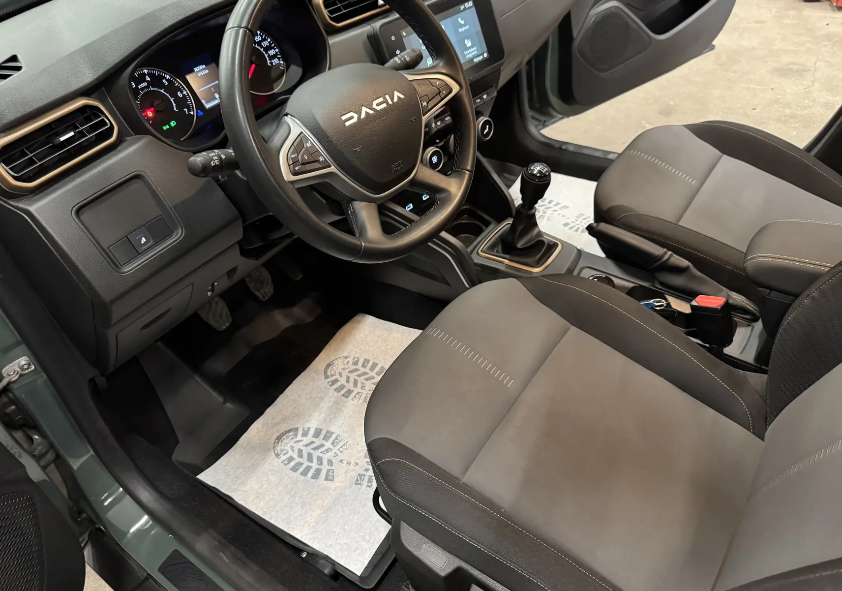 Vue intérieure côté conducteur du Dacia Duster 2024 kaki lichen, avec volant multifonction, tableau de bord digital et boîte manuelle.