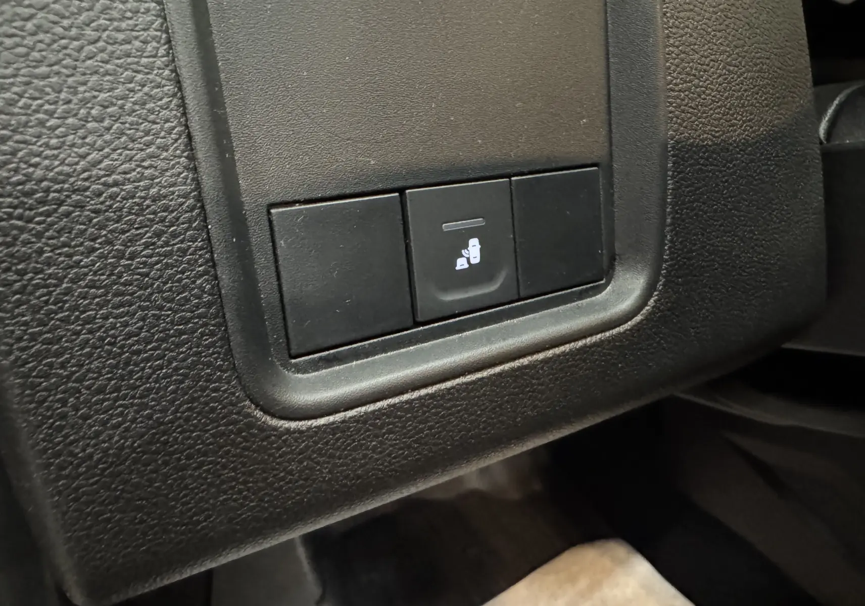 Bouton de commande d'ouverture du coffre intérieur sur tableau de bord noir du Dacia Duster 2024 kaki lichen.