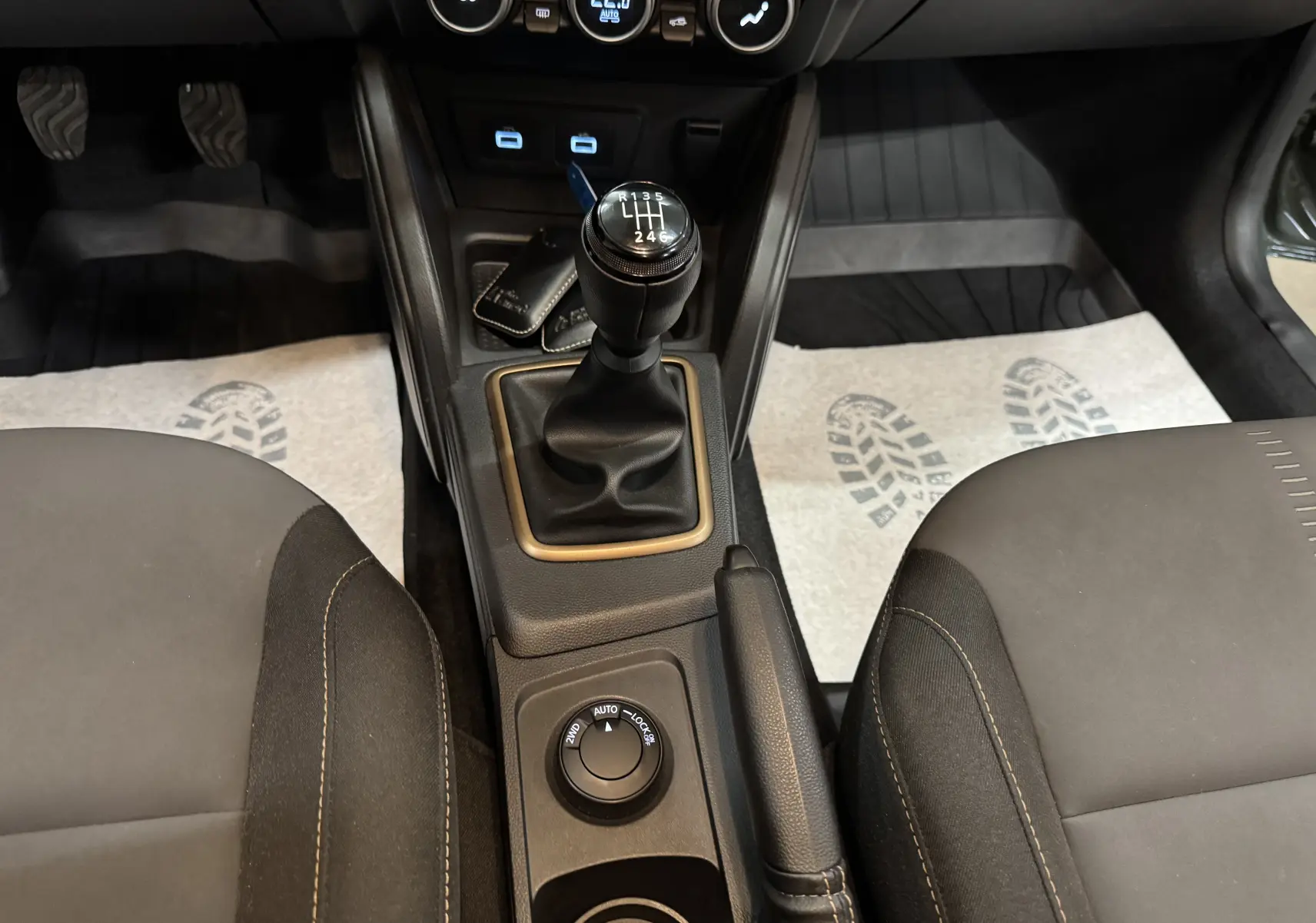 Vue intérieure centrée sur la console centrale du Dacia Duster 2024, montrant levier de vitesse manuel et commandes 4x4.